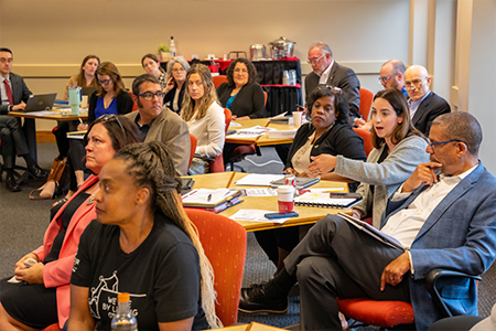 A diverse group of adults sit in a room having a discussion