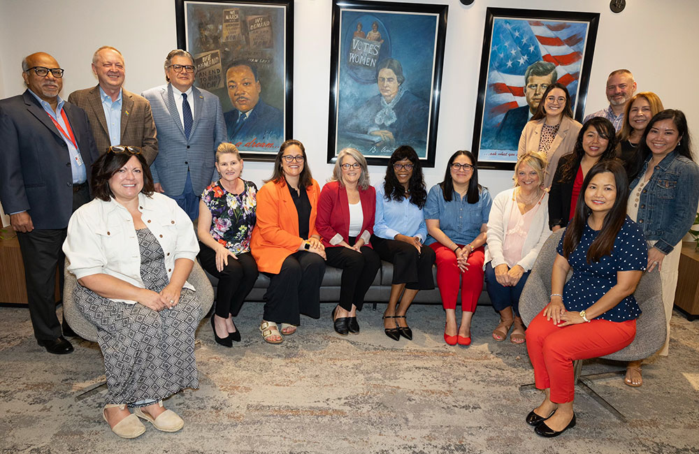 A group of diverse individuals pose together and smile at the camera.